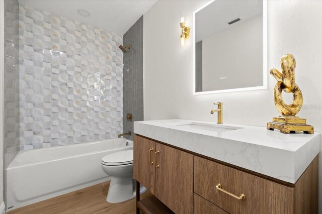 bathroom featuring visible vents, shower / tub combination, wood finished floors, vanity, and toilet