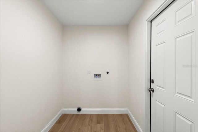 clothes washing area with laundry area, baseboards, hookup for a washing machine, electric dryer hookup, and light wood finished floors