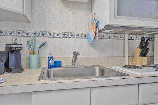 kitchen featuring white appliances, light countertops, white cabinets, a sink, and backsplash