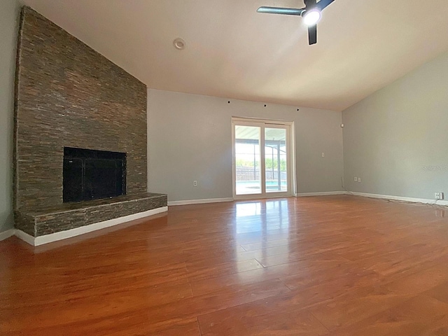 206 Westmoor Bnd, Orlando, FL 32835 - unfurnished living room with wood finished floors, baseboards, a stone fireplace, a ceiling fan, and vaulted ceiling