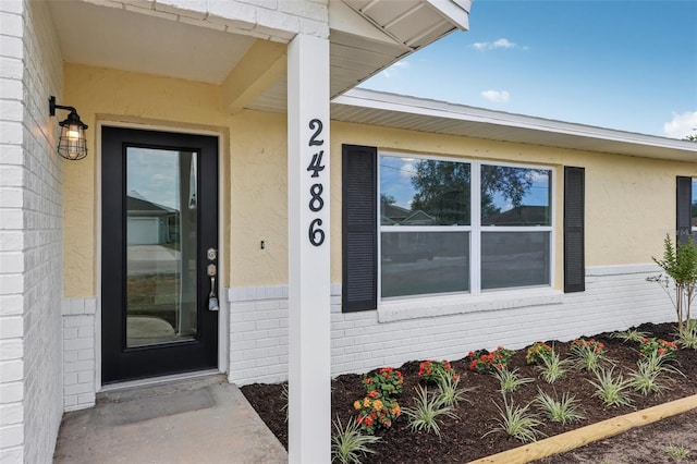 property entrance with stucco siding and brick siding