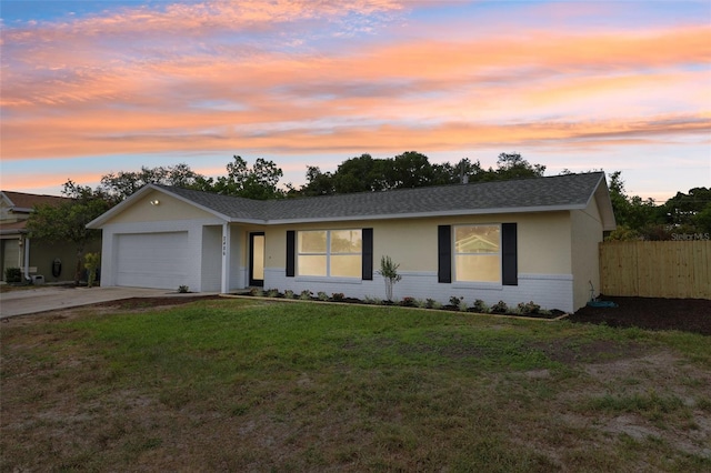ranch-style home with an attached garage, fence, concrete driveway, a yard, and brick siding