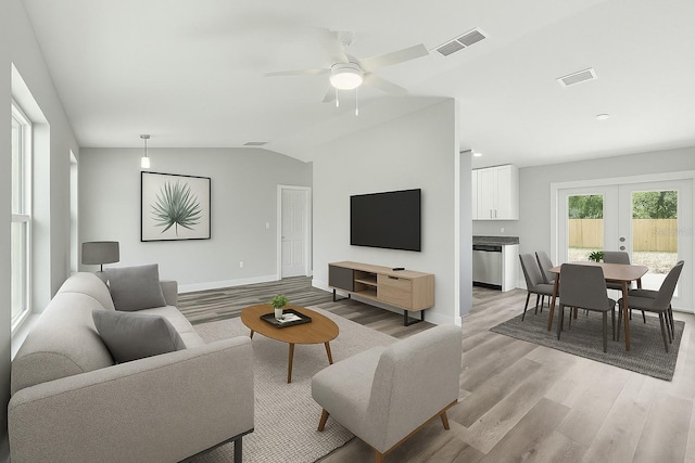 living room featuring lofted ceiling, french doors, light wood-style flooring, and visible vents