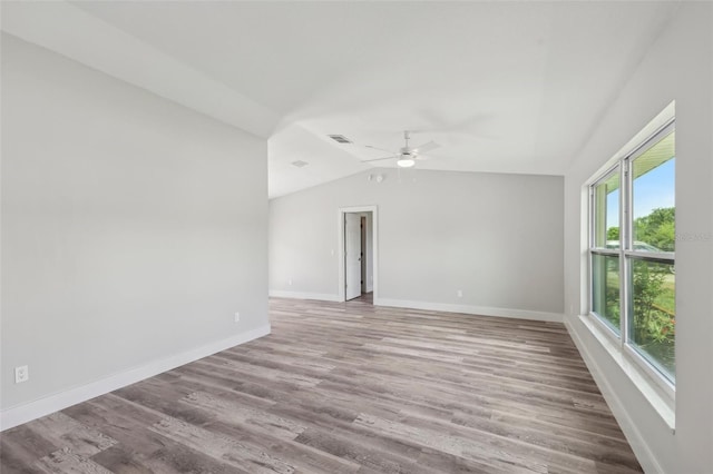 empty room with vaulted ceiling, ceiling fan, baseboards, and wood finished floors