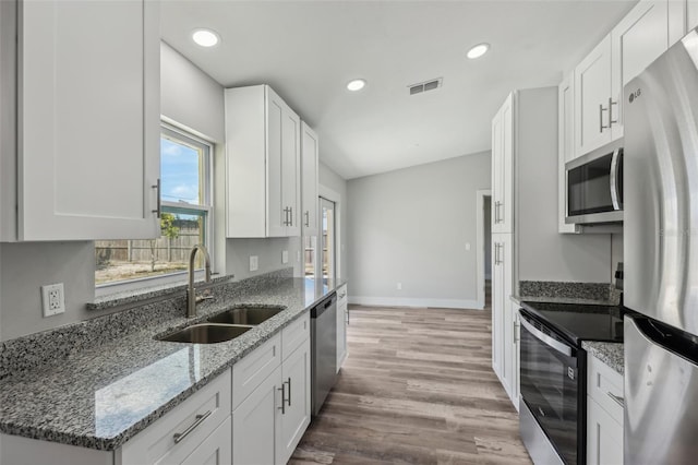 kitchen featuring a sink, light wood-style flooring, white cabinets, baseboards, and appliances with stainless steel finishes