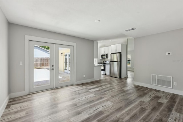 unfurnished living room featuring baseboards, french doors, visible vents, and wood finished floors