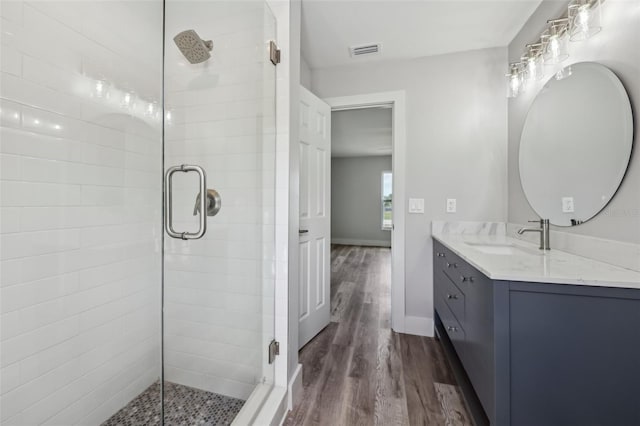 full bathroom featuring a shower stall, vanity, visible vents, and wood finished floors