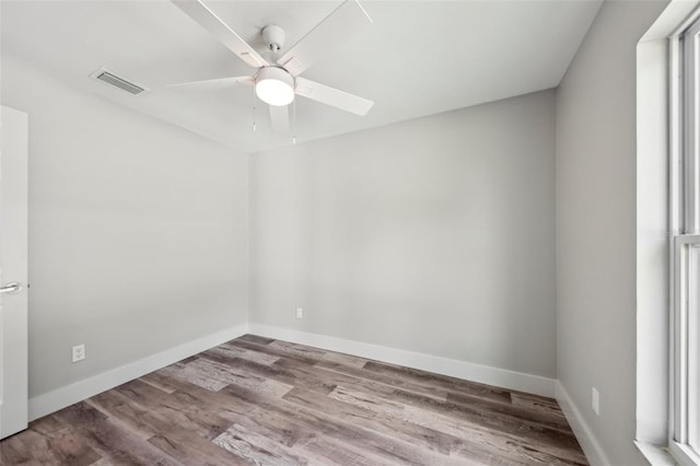 empty room featuring baseboards, visible vents, wood finished floors, and a ceiling fan