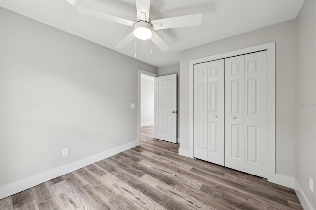 unfurnished bedroom with ceiling fan, baseboards, a closet, and wood finished floors