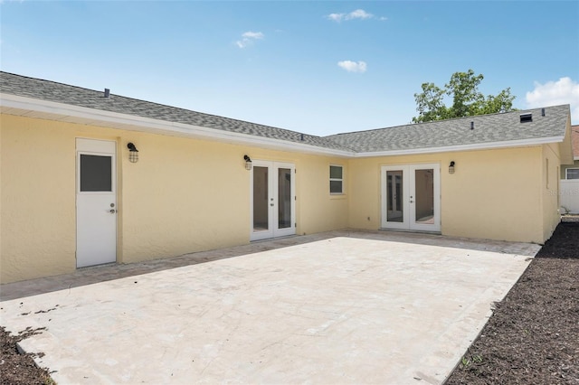 rear view of property with roof with shingles, a patio area, stucco siding, and french doors