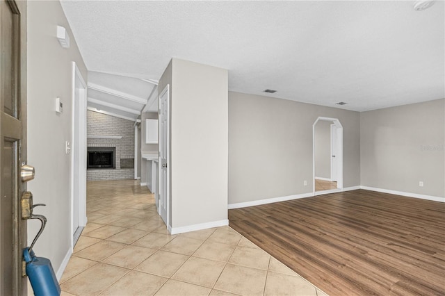 5788 Devon St, Port Orange, FL 32127 - unfurnished room featuring a brick fireplace, light tile patterned flooring, vaulted ceiling, and baseboards
