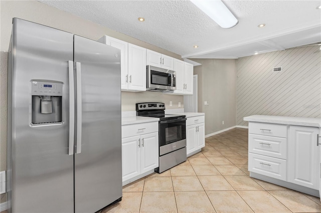 5788 Devon St, Port Orange, FL 32127 - kitchen featuring stainless steel appliances, light countertops, white cabinets, light tile patterned floors, and wood walls