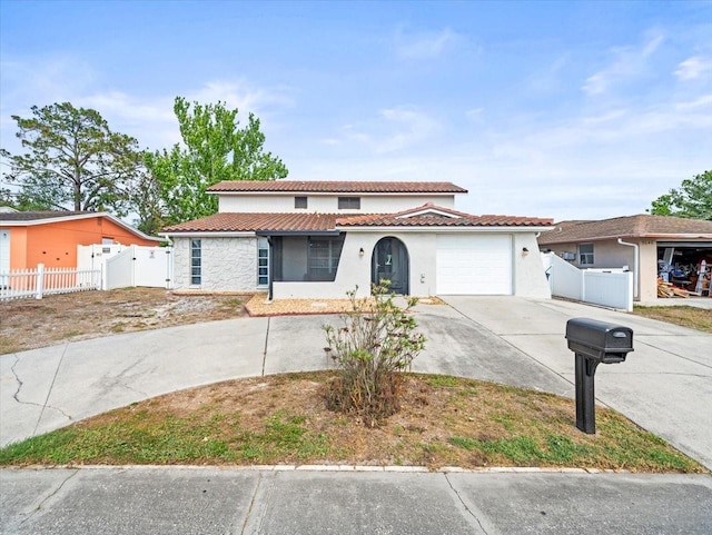mediterranean / spanish home with fence, a garage, stucco siding, a tiled roof, and driveway