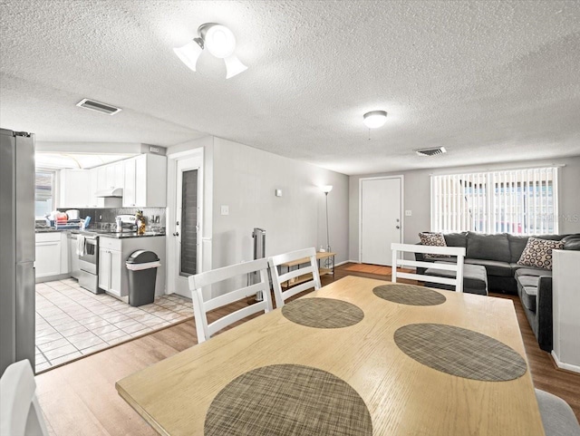 dining space featuring a textured ceiling, visible vents, and a healthy amount of sunlight