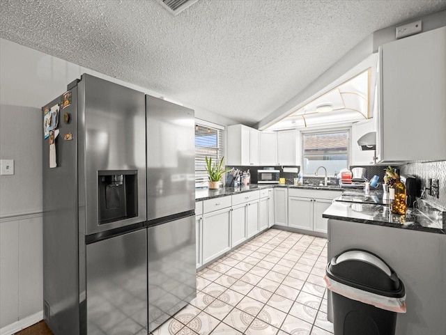kitchen featuring a healthy amount of sunlight, stainless steel appliances, a textured ceiling, and white cabinetry