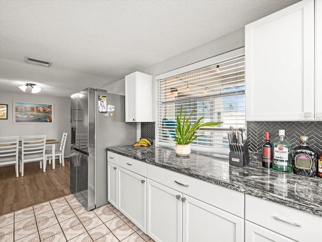 kitchen featuring freestanding refrigerator, a textured ceiling, visible vents, and decorative backsplash