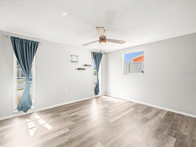 empty room featuring baseboards, a textured ceiling, ceiling fan, and wood finished floors
