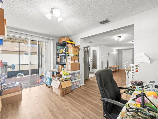 home office with visible vents, a textured ceiling, and wood finished floors