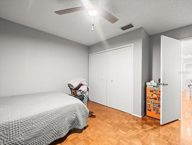 bedroom with a ceiling fan, a closet, a textured ceiling, and visible vents