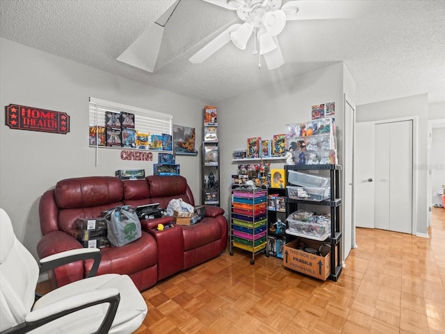 living room featuring ceiling fan and a textured ceiling