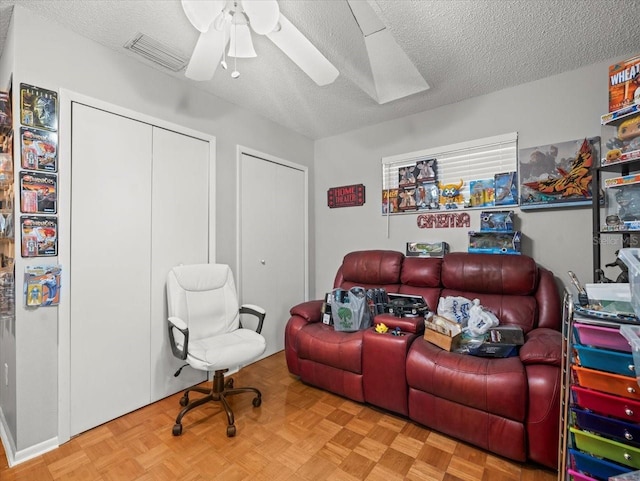 home theater room featuring a ceiling fan and a textured ceiling