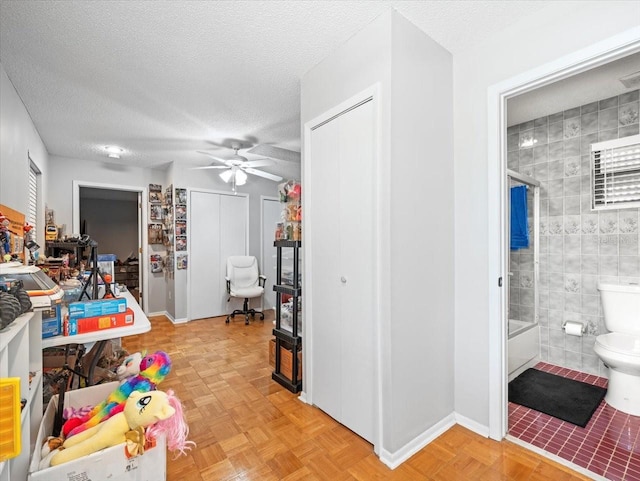 interior space with tile walls, ceiling fan, baseboards, and a textured ceiling