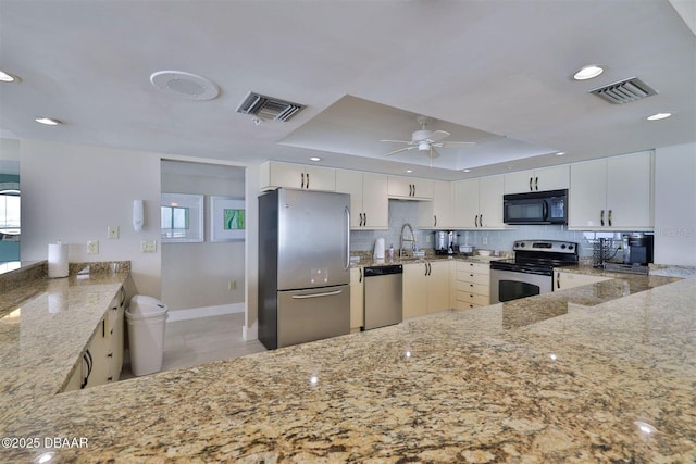 3855 S Atlantic Ave Unit 1405, Daytona Beach, FL 32118 - kitchen featuring stainless steel appliances, light stone countertops, visible vents, and a tray ceiling