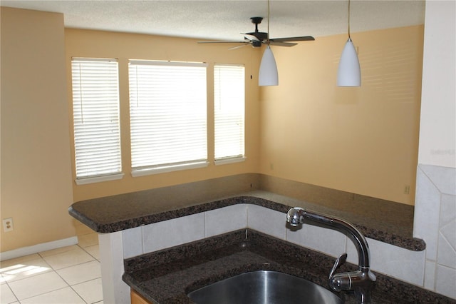kitchen featuring a sink, dark countertops, ceiling fan, and hanging light fixtures