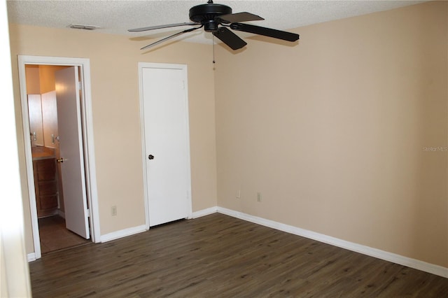 unfurnished bedroom with dark wood-type flooring, a textured ceiling, baseboards, and visible vents