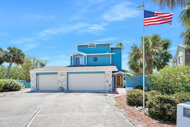 view of front of home featuring fence, an attached garage, concrete driveway, and stone siding
