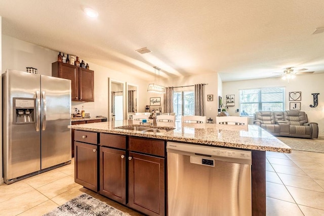 343 Lazio Cir, Debary, FL 32713 - kitchen with stainless steel appliances, a sink, light tile patterned flooring, open floor plan, and a center island with sink