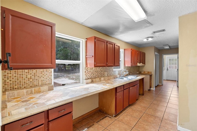 1560 7th Ave, Deland, FL 32724 - kitchen with a sink, a textured ceiling, light tile patterned floors, decorative backsplash, and healthy amount of natural light