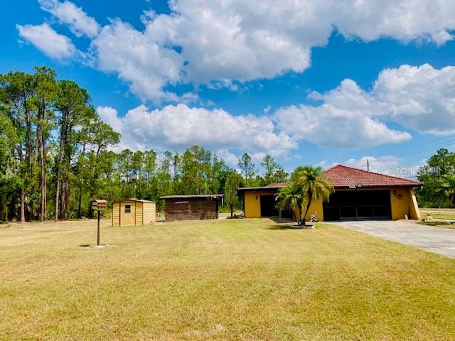 view of front of property featuring an outdoor structure, a garage, a storage unit, and a front yard