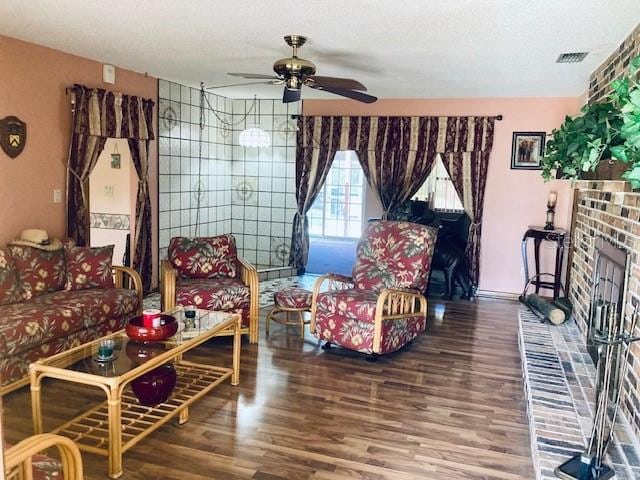 living room with ceiling fan, a fireplace, wood finished floors, and visible vents