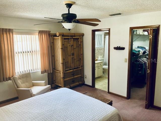 bedroom with visible vents, a textured ceiling, a walk in closet, and a closet