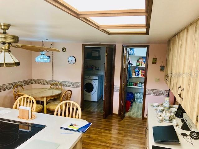 kitchen featuring light countertops, black electric cooktop, washer / clothes dryer, and wood finished floors