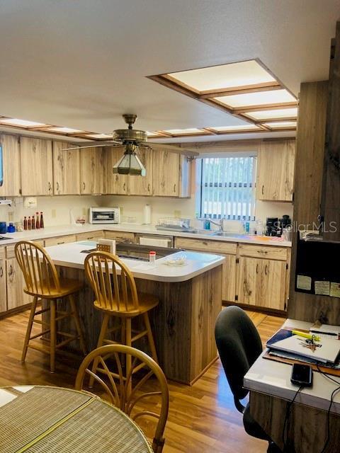 kitchen featuring light countertops, a kitchen breakfast bar, a kitchen island, and light brown cabinets