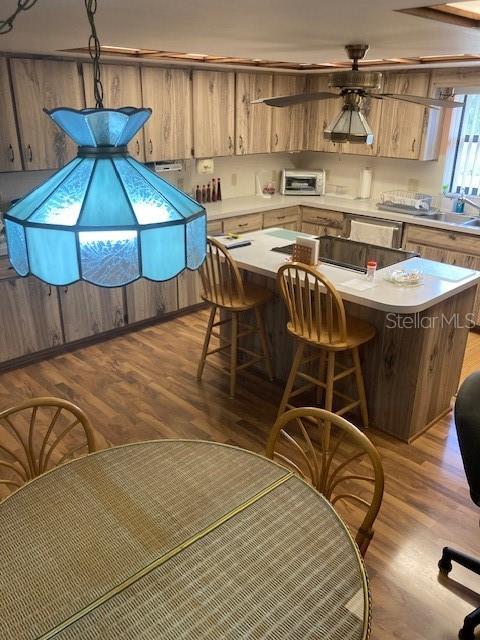 kitchen featuring wood finished floors, a kitchen island, a toaster, light countertops, and a sink