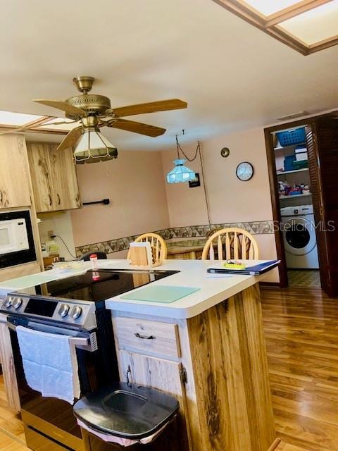 kitchen featuring washer / clothes dryer, light wood-type flooring, light countertops, stainless steel electric range, and a ceiling fan