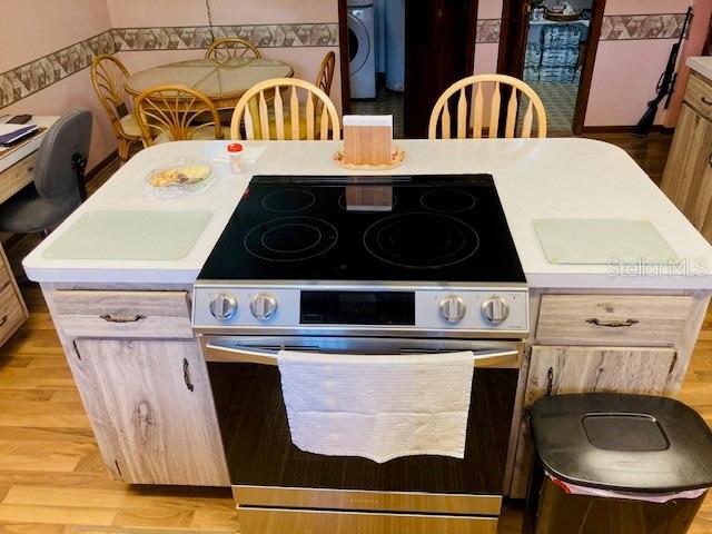 kitchen featuring light countertops, stainless steel range with electric cooktop, and light wood finished floors