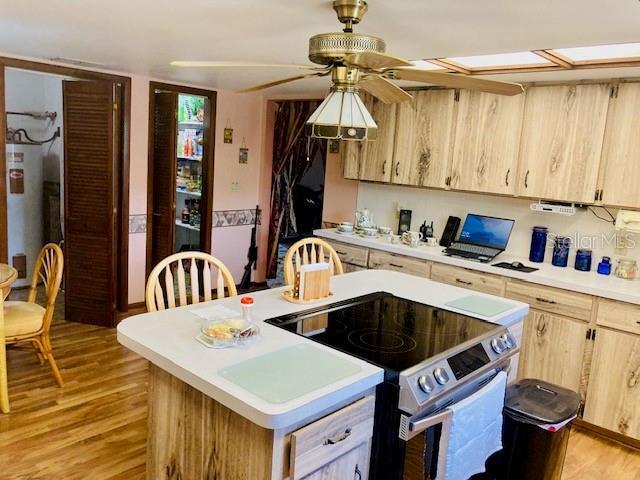 kitchen with light countertops, electric stove, light brown cabinetry, and electric water heater