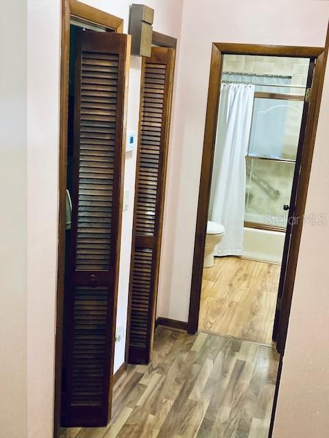 hall with baseboards and wood finished floors