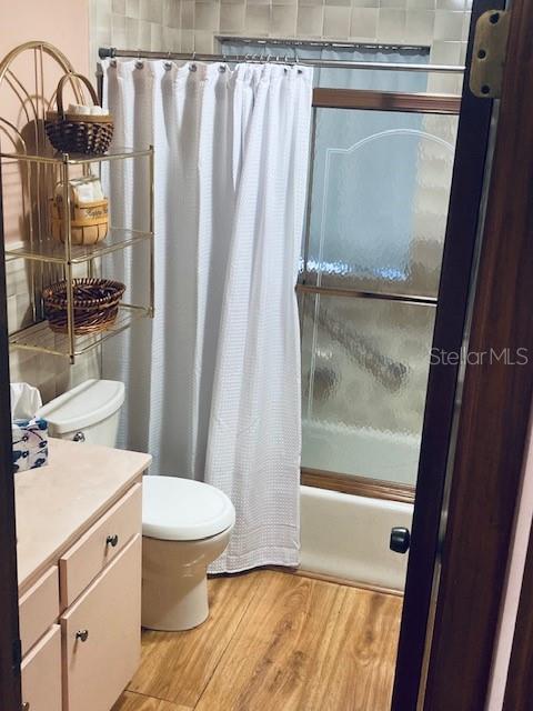full bath with vanity, toilet, wood finished floors, and shower / bath combination with curtain