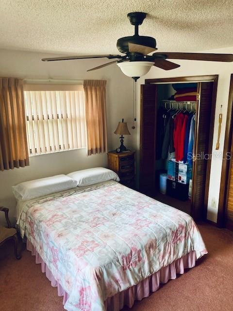 bedroom featuring carpet floors, a textured ceiling, ceiling fan, and a closet