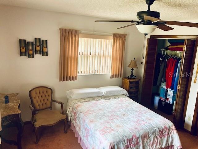 carpeted bedroom with a ceiling fan and a closet