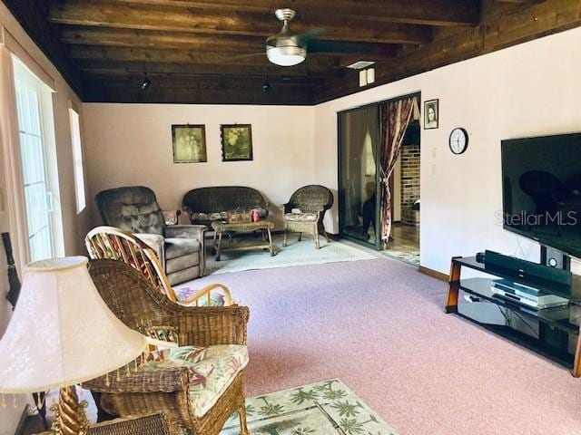 carpeted living room with baseboards and beamed ceiling
