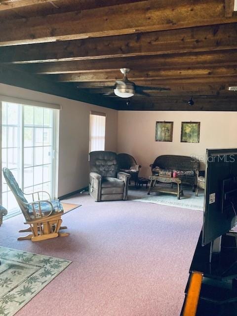 living area with beamed ceiling, ceiling fan, and carpet