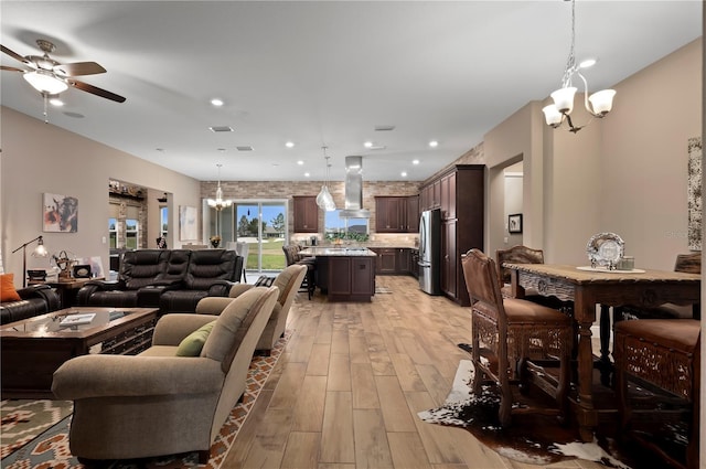 living area with recessed lighting, visible vents, light wood-style flooring, and ceiling fan with notable chandelier