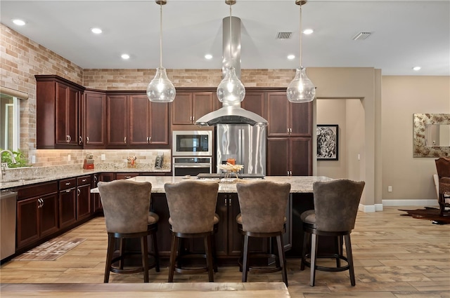 kitchen with backsplash, visible vents, a center island, light stone countertops, and stainless steel appliances