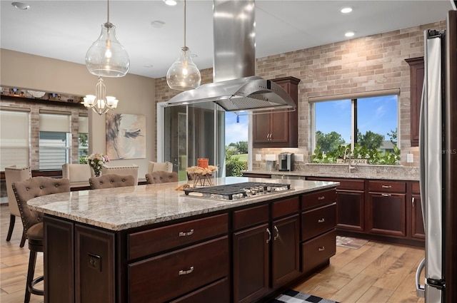 kitchen featuring a kitchen island, island range hood, light wood-type flooring, a breakfast bar, and stainless steel appliances